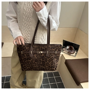 Detail of leopard print tote bag with brown leather strap and golden clasp closure