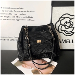 Detail of glossy wrinkled leather tote with gold twist lock and metal chain strap