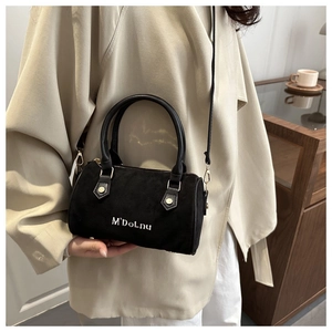 Sac Boston en daim noir tendance porté avec un trench-coat classique beige élégant