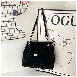 Detail of a black tote bag featuring crinkled texture and golden twist-lock closure