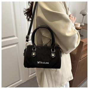 Détail du sac Boston en suède avec lettrage M'DoLnu et finitions dorées chic