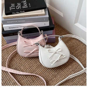Détail d'un mini sac demi-lune avec nœuds décoratifs posé sur un tapis en rotin