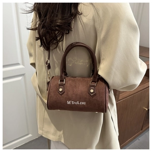 Détail du sac Boston en daim marron avec broderie blanche et finitions métalliques