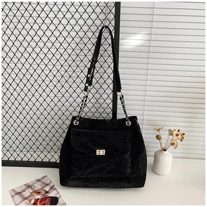 Detail of black large tote bag with retro pleated texture and golden twist lock closure