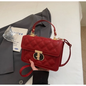 Close-up of red quilted leather handbag with gold metal clasp and elegant stitching