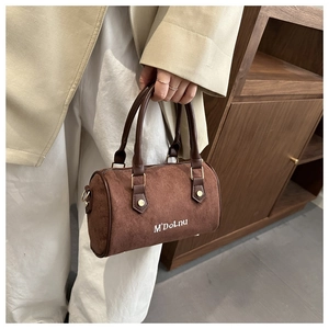 Gros plan du sac Boston marron avec texture en daim et détails métalliques dorés élégants