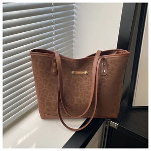 Dettaglio ravvicinato della borsa tote leopardata con emblema metallico e trama scamosciata