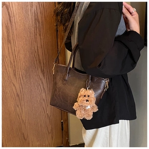 Sac seau marron avec breloque chiot en peluche et texture PU vintage sur un mannequin