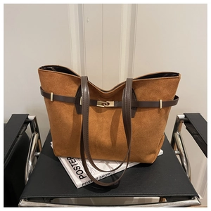 Macro detail of camel suede tote bag featuring brown leather straps and gold buckle