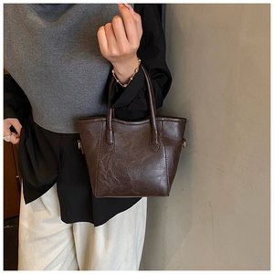 Détail d'un sac cabas en similicuir marron foncé avec texture vintage et poignées