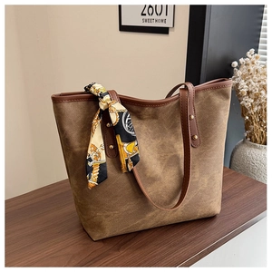 Close-up of brown canvas tote bag with leather handles and decorative printed silk scarf