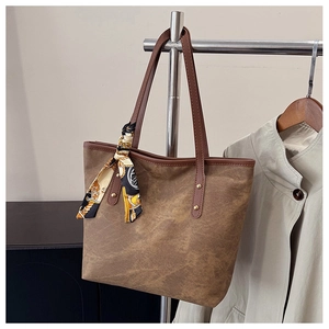 Close-up of brown tote bag with vintage scarf tied to the handle and gold rivet details
