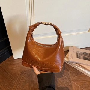 Glossy caramel brown half-moon handbag with gold H-buckle and embossed texture