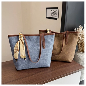 Detail of large canvas tote bag with leather straps and decorative silk scarf accessory