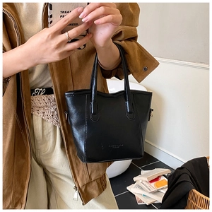 Gros plan d'un sac seau en cuir noir tenu par un mannequin pour un look décontracté