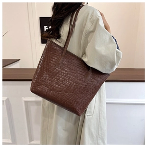 Deep brown woven tote bag on shoulder showing large capacity and stylish texture