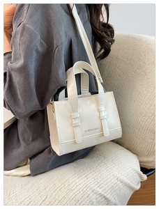 Close-up of white leather handbag featuring Fashion & Bags logo and gold hardware detail