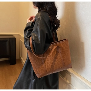 Detail of leopard print tote bag with brown leather trim and dual strap system