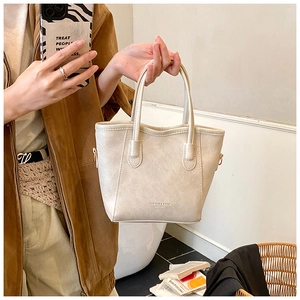 Détail d'un sac cabas en cuir texturé beige avec doubles poignées et texte imprimé