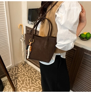 Detail of dark brown suede bucket bag featuring elegant beaded fringe pendant