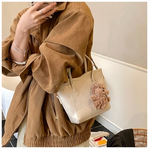Détail d'un sac seau beige en similicuir avec un charmant ours en peluche marron
