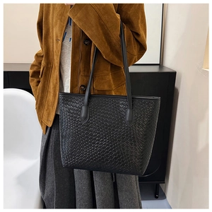 Detail shot of the black woven leather tote bag with a minimalist Intrecciato pattern