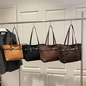 Minimalist large suede tote bags in assorted colors hanging on a modern display rack
