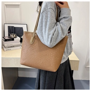 Detail of the woven texture and long strap on the brown tote bag worn by a model