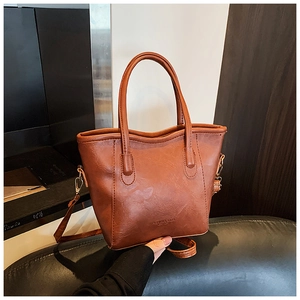Détail du sac seau en cuir marron montrant la texture naturelle et l'attache de l'anse