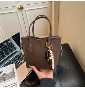 Close-up of deep brown matte tote bag with decorative wooden beads in a modern office set