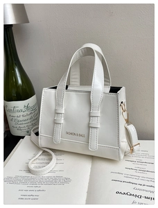 Detail view of cream structured tote bag with gold FASHION & BAGS lettering and thin strap