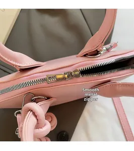 Gros plan sur la fermeture éclair en métal doré et la bandoulière du sac rose poudré
