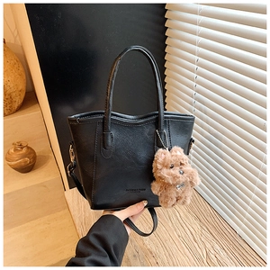 Détail d'un sac cabas noir en cuir grainé avec logo et breloque peluche ours décorative