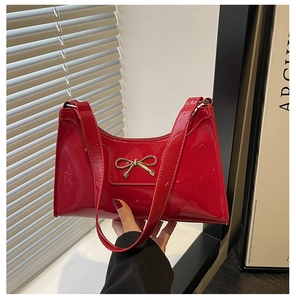 Detailed macro view of the glossy red patent leather finish and golden bow ornament