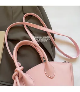Détail de la bandoulière réglable et de la texture en cuir du sac à main rose coquillage