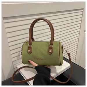 Detail view of the green suede Boston bag featuring brown leather straps and gold stud accents