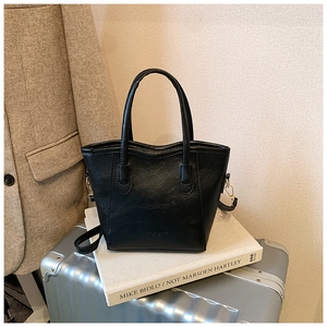 Détail du sac seau noir en similicuir avec finitions dorées sur des livres de mode