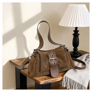Vue détaillée du sac en daim marron avec boucle vintage sur un tabouret en bois