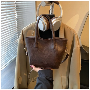 Détail du sac seau marron foncé en similicuir avec texte gravé et boucles dorées chic