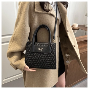 Détail d'un sac à bandoulière en similicuir noir matelassé avec nœud doré chic