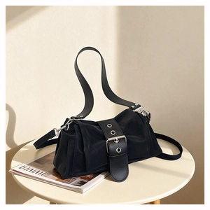 Détail du sac en nylon noir avec large bandoulière en cuir et boucle argentée