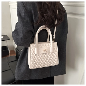 Vue détaillée d'un sac matelassé beige porté avec une veste blazer gris foncé