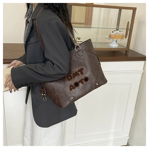 Detailed view of brown tote bag with DMT AOTO embroidery and metal buckle straps