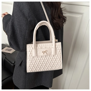 Chic cream quilted PU tote bag with gold bow clasp styled on dark grey wool coat