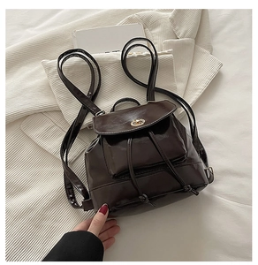 Detailed close-up of dark brown leather mini backpack with metal twist lock and drawstring