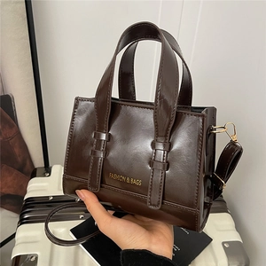 Classic dark brown glossy tote bag with double handles and fashion lettering for commuting