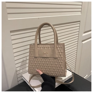 Détail de la texture losange matelassée beige sur le sac avec nœud doré élégant