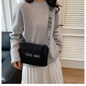 Detail of black corduroy crossbody bag with TOTE BAG embroidery and jacquard strap