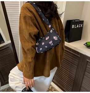 Floral print shoulder bag with pink bow pattern and black base material in detail view