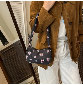 Detail of black quilted shoulder bag featuring pink rose floral and bow tie patterns